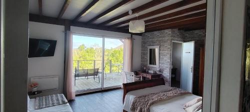 a bedroom with a bed and a view of a balcony at ETCHE ARGUINIA CHAMBRES HOTES et SPA in Montory