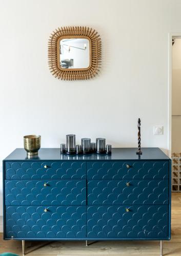a blue dresser with a mirror on the wall at Escapade du Stade BY UTA HOUSE in Saint-Denis