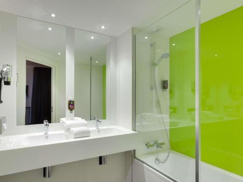 a bathroom with two sinks and a glass shower at ibis Styles Nantes Centre Gare in Nantes