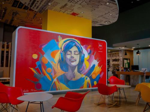 a painting of a woman on a wall with tables and chairs at ibis Copiapo in Copiapó