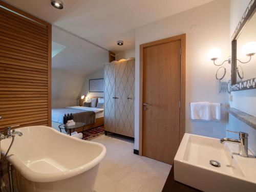 a bathroom with a sink and a tub and a bed at Mercure Belgrade Excelsior in Belgrade