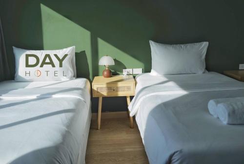two beds in a room with a nightstand between them at โรงแรมเดย์โฮเต็ล in Khon Kaen
