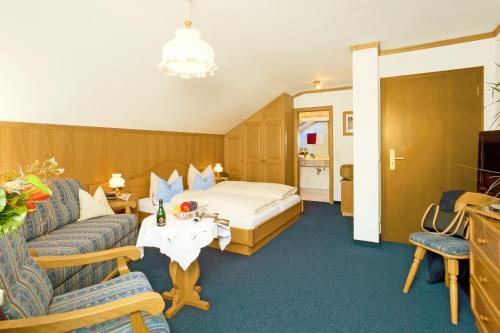 a hotel room with a bed and a couch at Hotel Landhaus Feldmeier ***S in Oberammergau