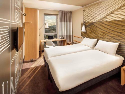 a hotel room with two beds and a desk at ibis London Canning Town in London