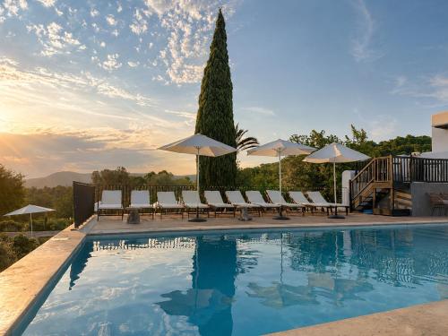 a swimming pool with lounge chairs and umbrellas at Can Skye in Sant Carles de Peralta