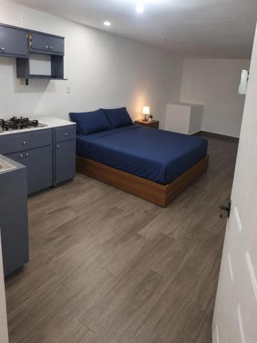 a bedroom with a blue bed and a kitchen at Loft Garden Santiago México in Santiago