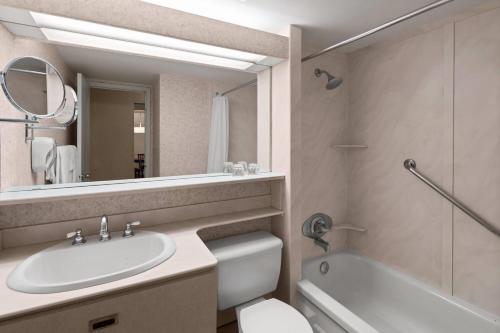 a bathroom with a sink and a toilet and a mirror at Royal Scot Hotel & Suites, Trademark Collection by Wyndham in Victoria