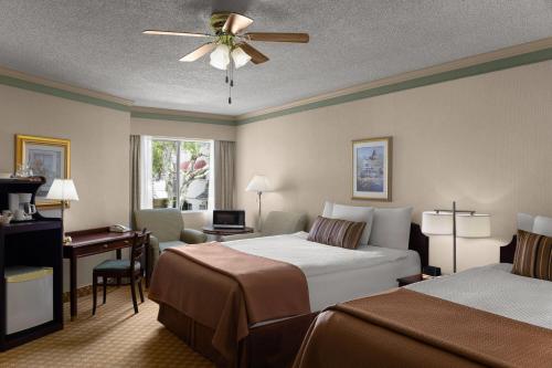 a hotel room with two beds and a ceiling fan at Royal Scot Hotel & Suites, Trademark Collection by Wyndham in Victoria