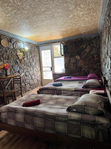 drei Betten in einem Zimmer mit Steinwand in der Unterkunft SADA Guesthouse in Wardsia
