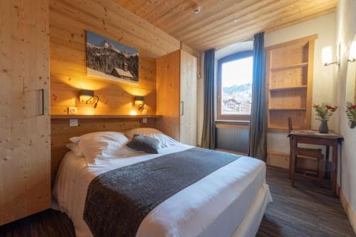 a bedroom with a large bed in a wooden room at Hotel la Pointe Percee in Le Grand-Bornand