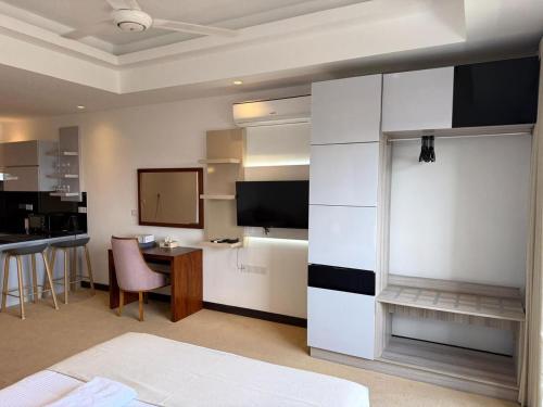 a room with a bed and a desk and a tv at Ocean Breeze Residencies in Negombo