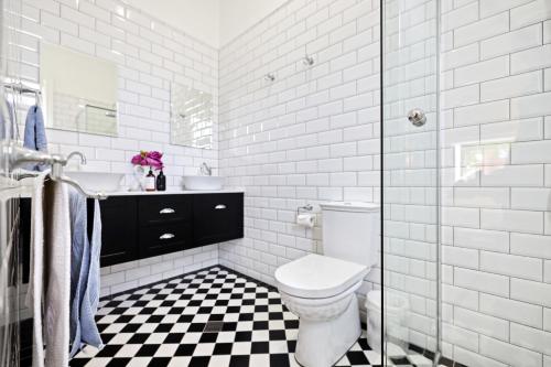a white bathroom with a toilet and a sink at Roseberne Cottage, Luxury in the CBD! in Bathurst