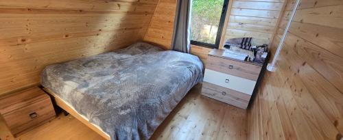 a small bed in a wooden room with a window at Cottage Sunset 2 in Sakhalvasho