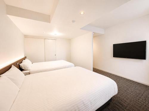 two beds in a room with a flat screen tv at Residence Hotel Liberte in Sapporo