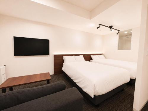 a hotel room with two beds and a couch at Residence Hotel Liberte in Sapporo