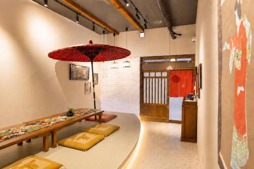 a room with a table and a red umbrella at Kimono Hotel Himeji 着物宿 in Himeji