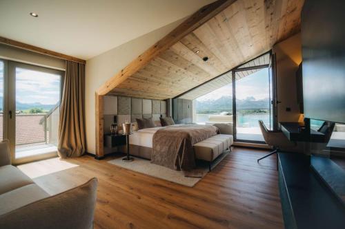a bedroom with a large bed and large windows at Hotel am Hopfensee in Füssen