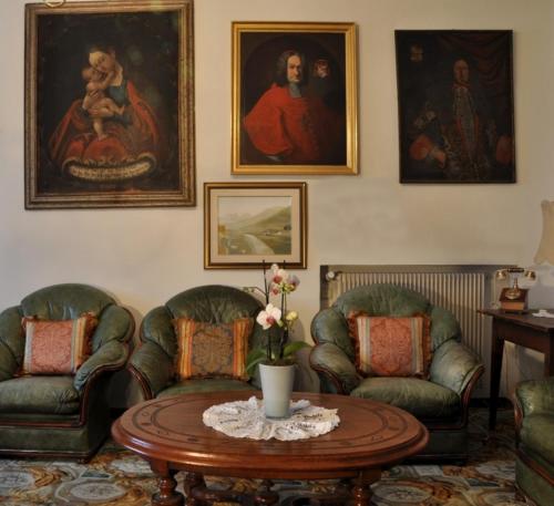 a living room with two chairs and a table and paintings at Hotel Ansitz Kandelburg in Mühlbach
