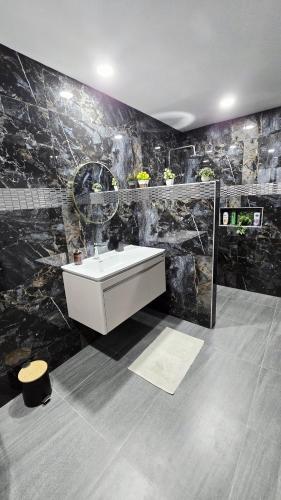 a bathroom with a sink and a black marble wall at Villa des Princes in Ban Thung
