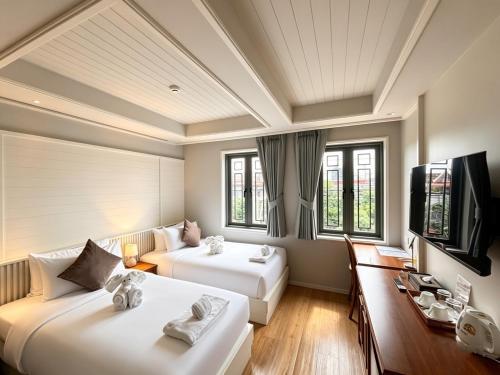 a hotel room with two beds and a desk at TUAN Hotel Bangkok near Wat Arun in Bangkok Yai