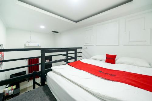 a bedroom with a bed with a red blanket at JM Guest House Lamaran RedPartner in Karawang