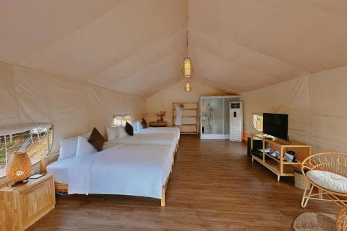 a large bedroom with two beds and a television at La Vela Legacy Resort in Thôn Dương Xuân Hạ