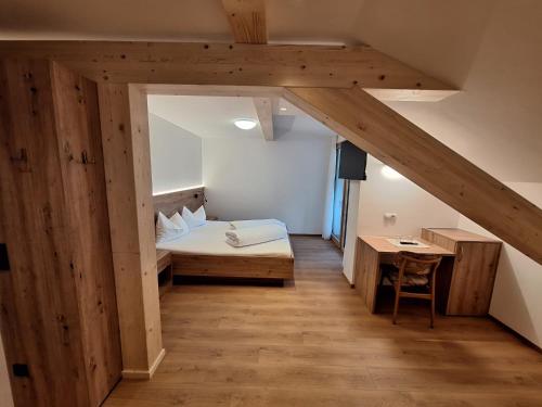 a bedroom with a bed and a desk in a room at Hotel Pörnbacher in Valdaora
