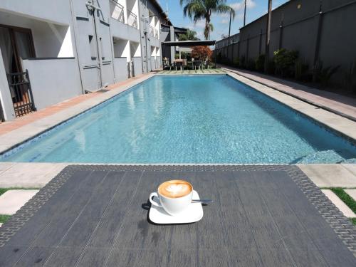 a cup of coffee sitting on a table next to a pool at Grand Palace Hotel Lusaka in Lusaka