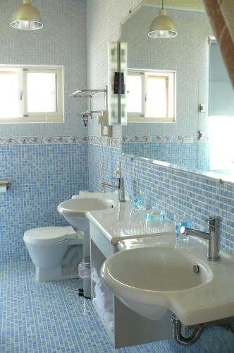 a blue tiled bathroom with two sinks and a toilet at Sunrise B&B in Huxi