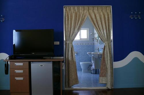 a bathroom with a tv and a blue wall at Sunrise B&B in Huxi