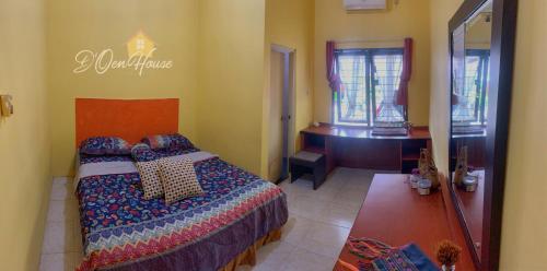 a bedroom with a bed and a desk in a room at D'Oen House Banjarbaru in Banjarbaru