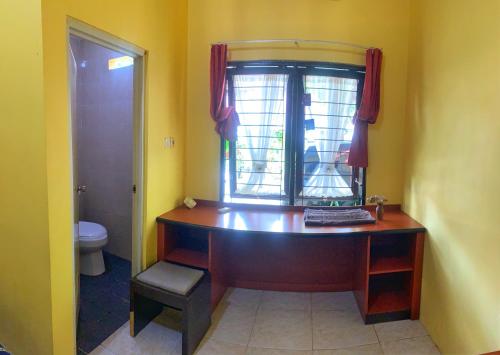 a bathroom with a wooden desk and a window at D'Oen House Banjarbaru in Banjarbaru