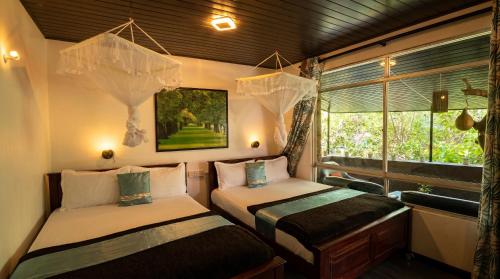 two beds in a room with a window at Ella green stay in Ella