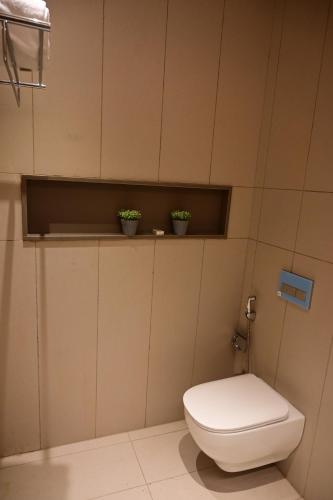 a bathroom with a toilet and two potted plants at Club Charholi in Lohogaon
