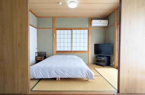 a bedroom with a bed and a flat screen tv at 伊根の宿 汐風 Shiokaze in Nomuro