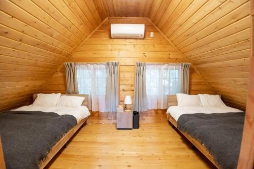 a bedroom with two beds in a wooden cabin at Mtd大分天ヶ瀬 in Hita