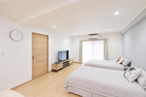 two beds in a white room with a tv at Room 501 Japanese Tatami 3LDK 75sqm Near Namba Family Friendly Stay in Osaka