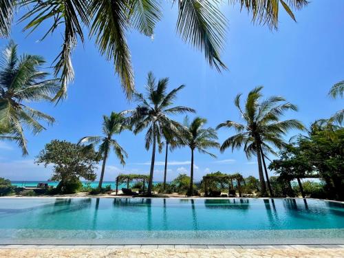 a pool with palm trees on the beach at Kizikula - Boutique Hotel in Kizimkazi