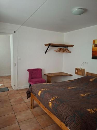a bedroom with a bed and a pink chair at NORDIQUES DE LA WELCHE in Orbey