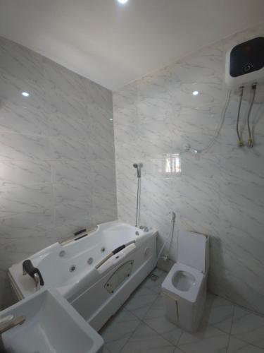 a white bathroom with a tub and a toilet at House 27 Alpha in Idu