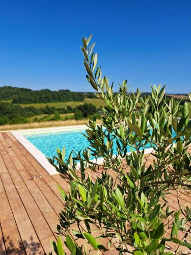 a swimming pool next to a wooden deck at Lôu cayrou in Beaumarches