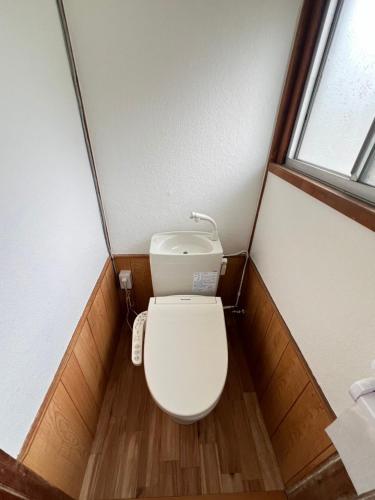 a toilet in a small bathroom with a window at 民泊びんご1 in Onomichi