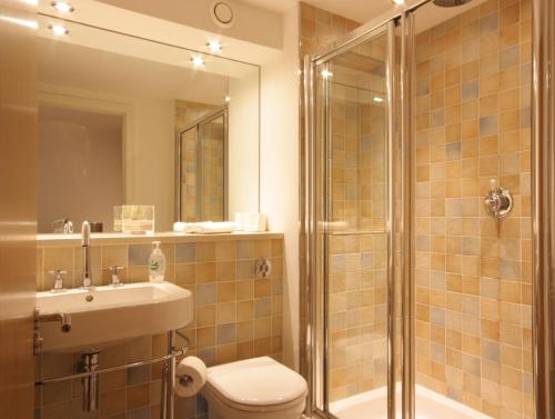 a bathroom with a shower and a toilet and a sink at By The Bridge Apartments in Inverness