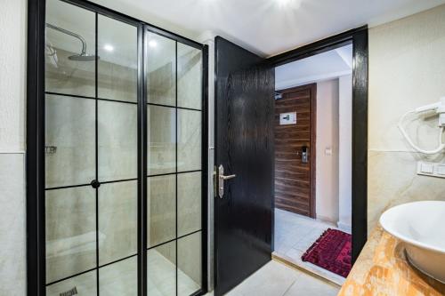 a bathroom with a glass shower door and a sink at Çınar Butik Hotel in Kaş