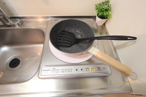 a frying pan on a stove with a spatula at LUANA in KICHIJOJI in Musashino