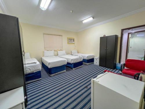 a room with four beds and a red chair at فندق مهوى الفؤاد 1 ذاخر توصيل مجاني للحرم Mahwa Alfoad 1 Hotel free bus to Haram in Mecca