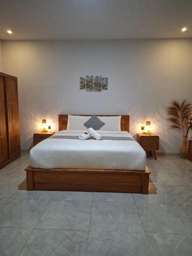 a bedroom with a large bed with two lamps on either side at Rumah Asri Devarastra #1 in Amed