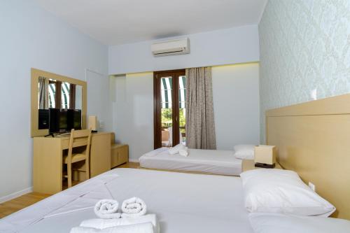 a hotel room with two beds and a television at Aphrodite Hotel Syros in Kini
