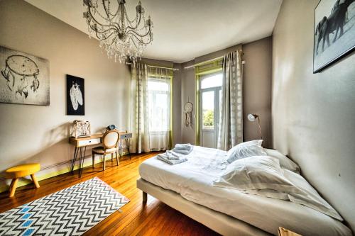 a bedroom with a large bed and a chandelier at La Canopée in Verdun-sur-Meuse