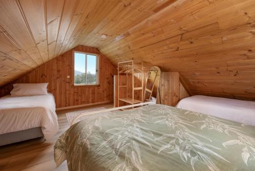 a bedroom with two beds in a wooden cabin at Rivendell Cottage - Off Grid cabin in Jackeys Marsh